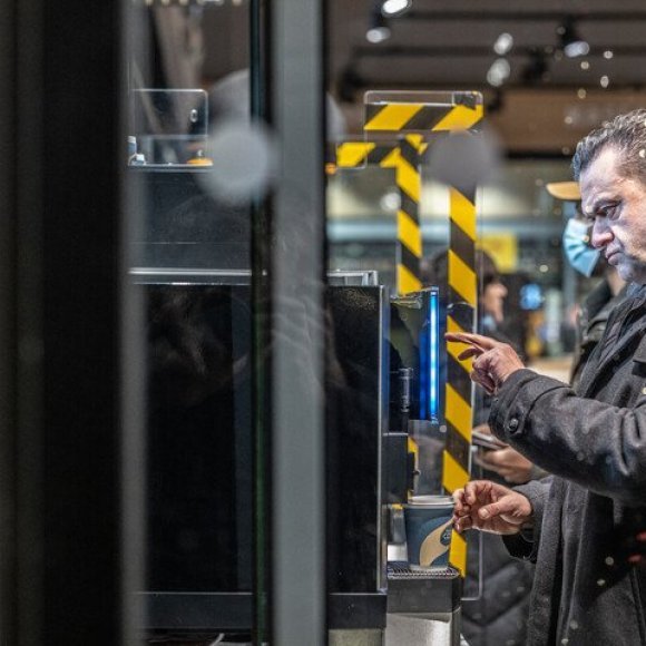 man die koffie uit automaat neemt in tankstation