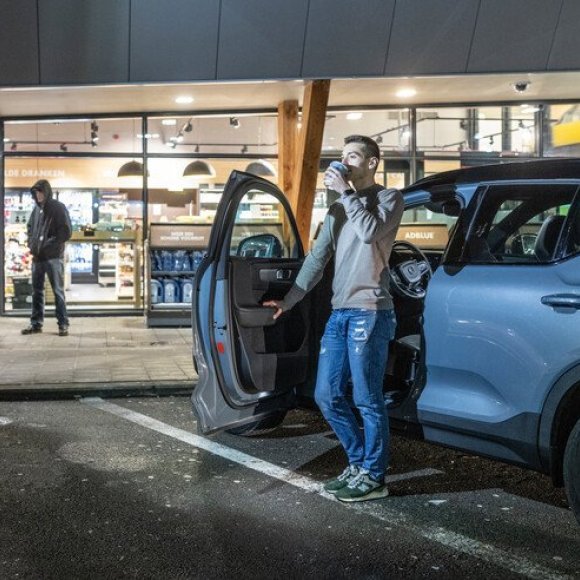 man die uit auto stapt op parking tankstation, buiten donker