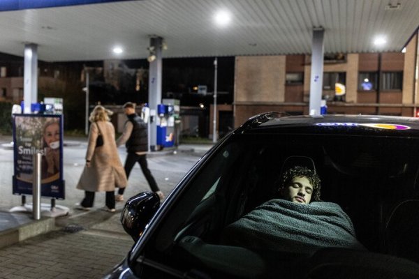 vrouw die powernap doet in auto op parkeerplek aan tankstation