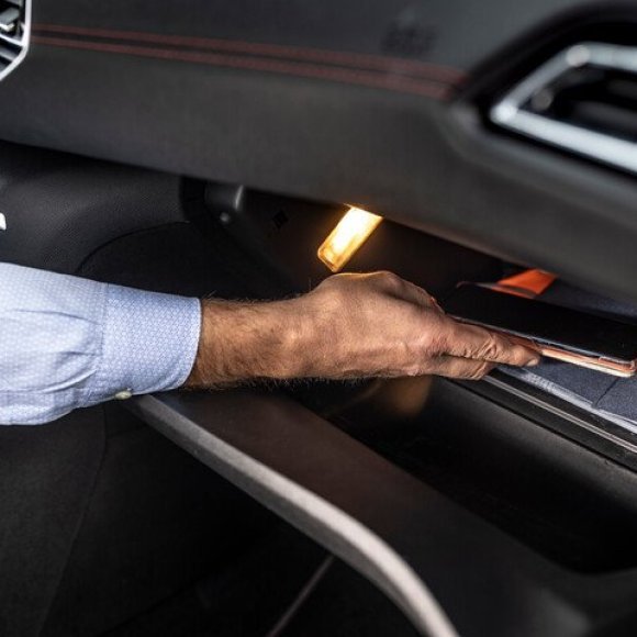 Man die gsm in handschoenenkastje van de auto legt