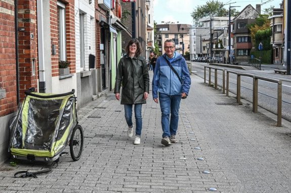 voetgangers op voetpad naast geparkeerde fietskar