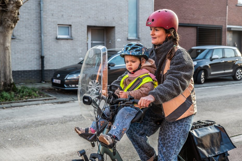 moeder die fietst met kind in fietsstoeltje vooraan op de fiets