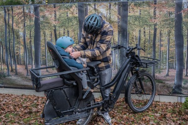 man die kind vastzet in fietsstoel op longtailfiets