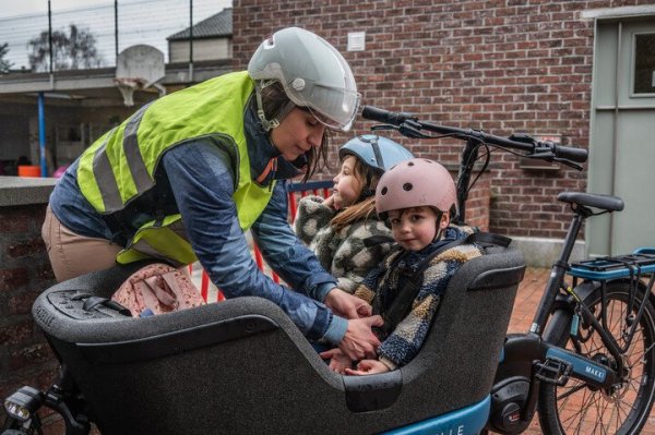 moeder die kinderen in een bakfiets zet
