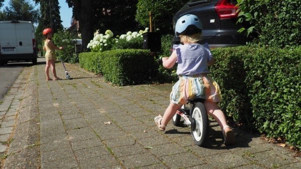 meisje op een loopfiets op het voetpad