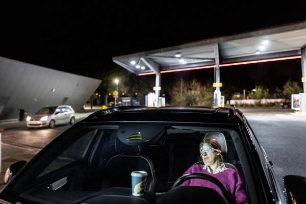 vrouw die powernap doet in de auto op parking van een tankstation