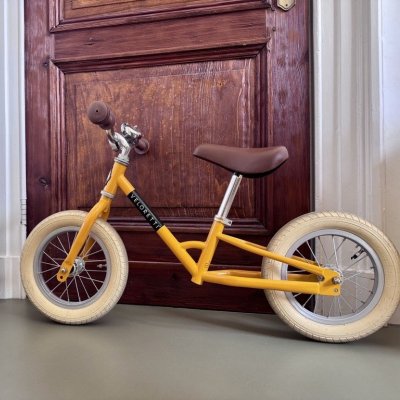 loopfiets die binnen in een woonkamer tegen een deur staat